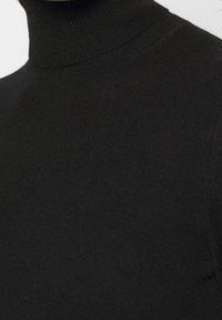 Maglione a collo alto in morbido tessuto lavorato a maglia, caratterizzato da un colletto alto e una texture a coste, con una vestibilità aderente.