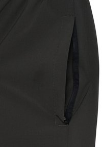 Lomme i sort stofbuks med delvist åben sort lynlås, der viser lynlåsens tænder og trækstykke på højre side.