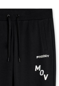 Pantalones de chándal negros con cintura elástica, cuerda de ajuste negra, bolsillo lateral y texto blanco "FREDDY" y "MOV" en el muslo.
