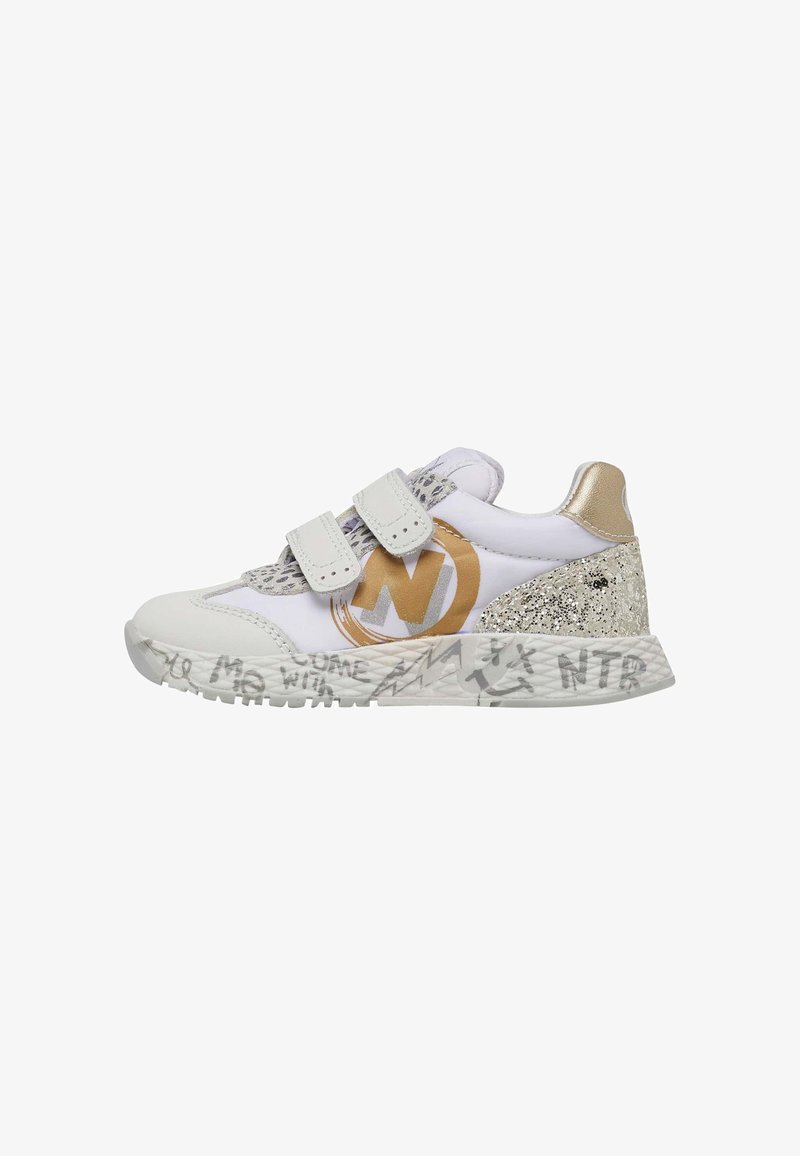 Sneaker blanche avec accents dorés et bandes Velcro. Présente un talon scintillant et une semelle texturée avec des écritures de style graffiti.