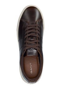 Brown leather sneaker with a smooth finish, rounded toe, and contrasting white rubber sole. Features brown laces and embossed logo.