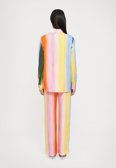Barevný dvoudílný outfit s dlouhými rukávy, pruhovaný design v růžové, žluté, zelené a modré barvě, s volným střihem a širokými kalhotami.