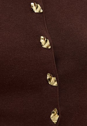 Tissu côtelé marron foncé avec quatre boutons décoratifs en forme de feuille dorée brillants disposés verticalement.