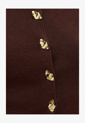 Tissu côtelé marron foncé avec quatre boutons décoratifs en forme de feuille dorée brillants disposés verticalement.