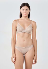 Bralette in pizzo e mutandine abbinate in beige chiaro. Il reggiseno ha bordi scallop e sottili spalline regolabili; le mutandine presentano un dettaglio a fiocco.