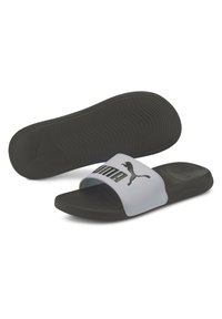 Chanclas en blanco y negro que presentan una suela de goma negra texturizada y una tira sintética ancha con un logotipo en relieve.