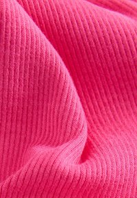 Primo piano di un tessuto a maglia rigata di un rosa brillante, con texture e pieghe visibili.