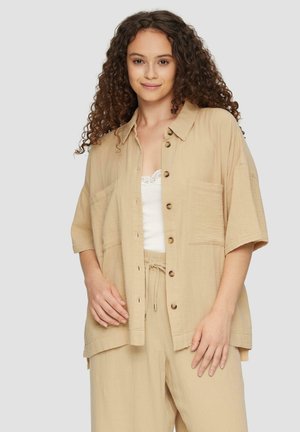 Beige shirt met korte mouwen van gestructureerde stof, voorzien van een knoopsluiting aan de voorkant, twee borstzakken en een ontspannen pasvorm.