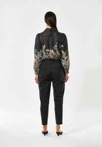 Black shirt with colorful floral embroidery along the hem; paired with tailored black pants and pointed-toe heels.