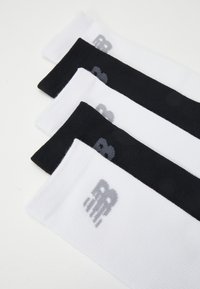 Four pairs of athletic socks in black, white, and gray. Made from textured fabric, featuring a small logo on the cuff.