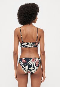 Blomstrete bikini-sett med svart bakgrunn. Har en foret bandeau-top med tynne stropper og matchende undertøy. Glatt stoff med et levende mønster.