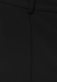 Tissu noir avec une texture lisse, présentant une couture verticale et une taille. Le matériau semble doux et durable.