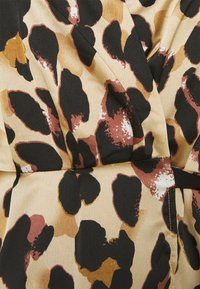 Tissu avec un imprimé léopard présentant de grandes taches noires, brunes et dorées sur un fond crème, avec une texture lisse et légèrement brillante.