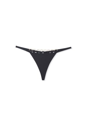 Las braguitas negras tipo tanga presentan una tela suave con un corte de baja altura, decoradas con acentos circulares dorados a lo largo de la cinturilla.