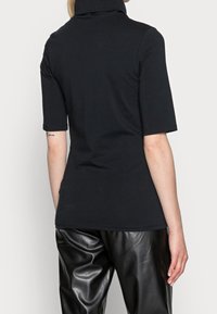 Camisa de cuello alto de manga corta negra, hecha de una tela suave, con un corte ajustado y un cuello alto y doblado.