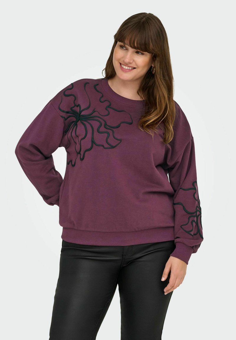 Sudadera de color púrpura con un diseño floral en negro en ambas mangas, hecha de un material suave con un corte relajado y puños de canalé.