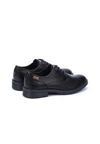 Chaussures en cuir noir avec une pointe ronde et un design à lacets. Présentent une semelle extérieure bleue contrastante et un petit accent en cuir beige sur le côté.