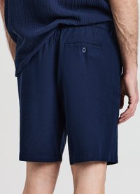 Marineblaue Shorts aus strukturiertem Stoff, mit elastischem Bund und einer Gesäßtasche mit Knopfverschluss.