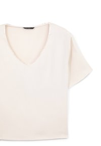 Blusa corta color crema con maniche a sbuffo e scollatura a V, in tessuto liscio, con un'etichetta nera che riporta la scritta "CALLIOPE S" all'interno del colletto.