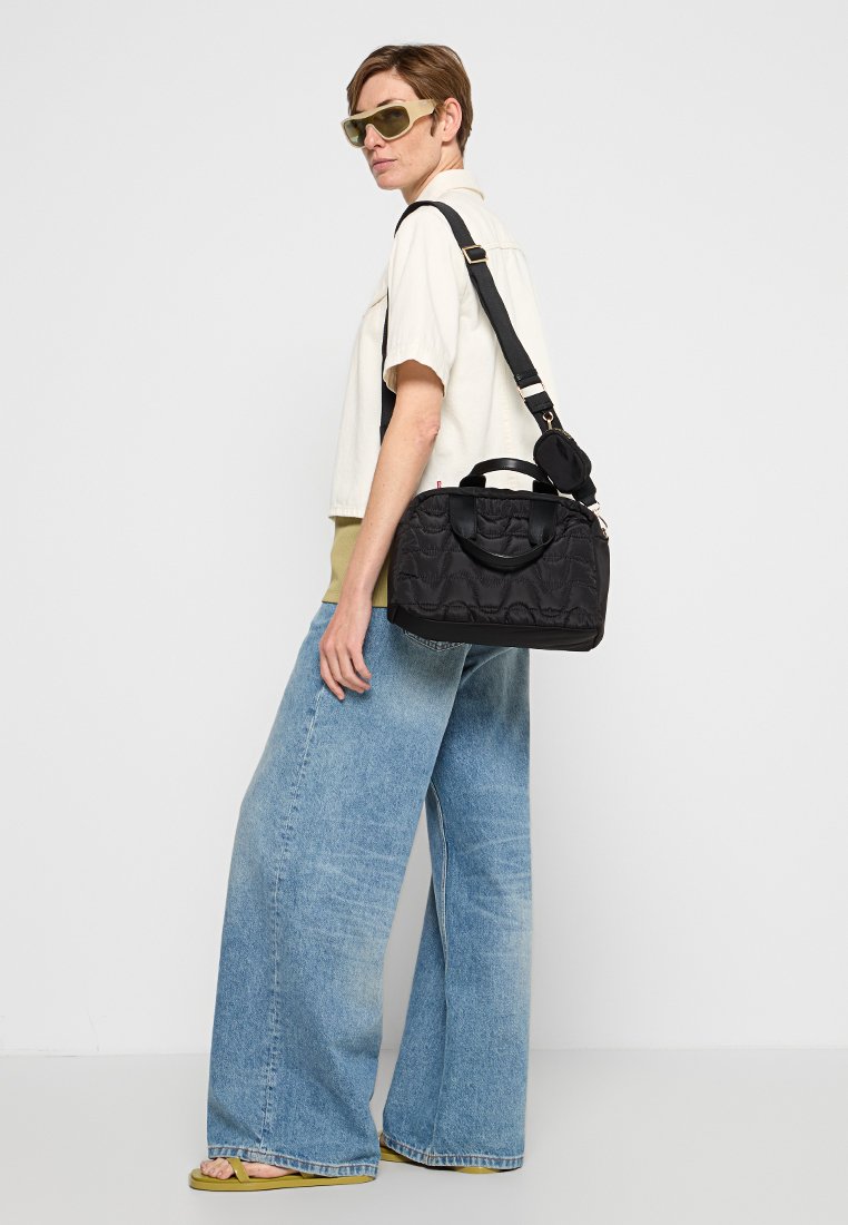 Czarna pikowana torebka z podwójnymi uchwytami i odpinanym paskiem na ramię. Charakteryzuje się gładką teksturą i kompaktowym designem.