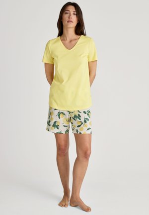 T-shirt en coton jaune à col en V associée à un short à motif citron en blanc et vert. La tenue présente des manches courtes et une coupe décontractée.