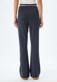 Marineblauwe wijde broek van ribbelstof, met een hoge taille en subtiele verticale strepen. De onderrand is netjes en niet omgezoomd.