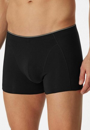 Black boxer shorts made of soft cotton, featuring a snug fit, elastic waistband with a thin light-colored trim, and flat seams for comfort.
