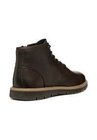 Botte chelsea en cuir marron avec un bout arrondi, une finition texturée et des lacets noirs. Dotée d'une semelle en caoutchouc légèrement crantée pour une meilleure adhérence.
