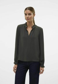 Donkergroene blouse met lange mouwen, gerimpelde kraag en manchetten. Textuurstof met een ontspannen pasvorm en een V-hals. Gemaakt van zachte materialen.