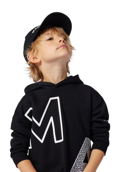 Felpa nera con grande logo bianco a "M" e motivo laterale. Completata da un berretto nero, con un logo sulla parte anteriore.