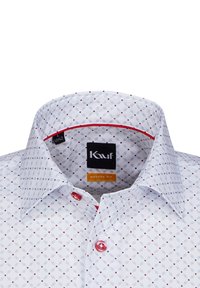 Camicia bianca con vestibilità moderna, caratterizzata da un motivo geometrico blu e rosso, chiusura con bottoni, un singolo bottone rosso e un accento rosso all'interno del colletto.