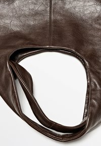 Sac à main en cuir marron foncé avec une poignée arrondie et des coutures visibles, présenté sur un fond blanc.