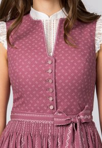 Rosa blumenmuster Kleid mit tiefem V-Ausschnitt, kleinen Knöpfen vorne und einem gesmokten Bund. Mit einem kontrastierenden weißen Kragen und einer Schleife.