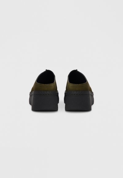 Πράσινα χακί παπούτσια χωρίς κορδόνια με υφή δερμάτινου πάνω μέρους, μαύρη λαστιχένια σόλα και ελάχιστες ραφές, φαίνονται από πίσω.