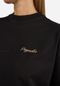 Zwarte katoenen sweatshirt met een hoge halslijn, voorzien van een gouden geborduurd "Pegador" logo aan de linkerkant. Soepele textuur, casual pasvorm.