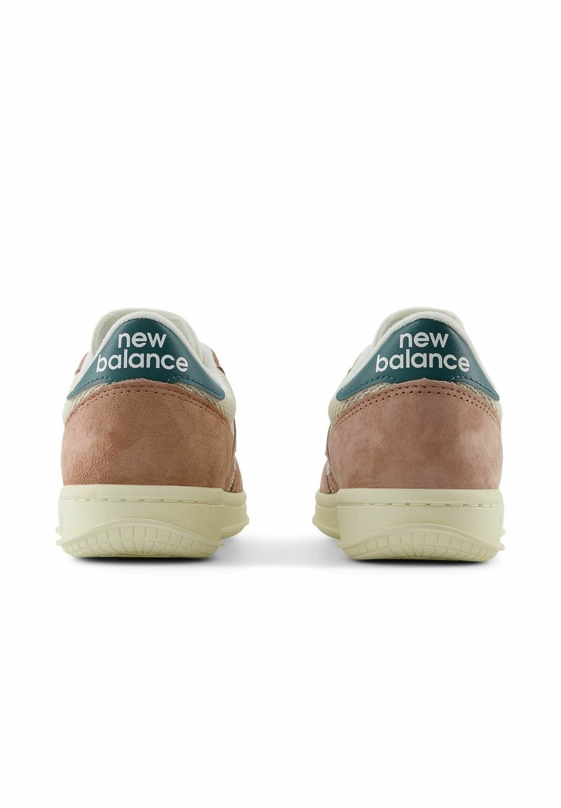 Zapatillas New Balance con parte superior de ante en rosa claro, acentos blancos y lengüeta en color aguamarina. Presenta suelas texturizadas y logo de la marca en el talón.