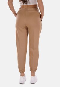 Pantaloni jogger color beige realizzati in morbido materiale, con vita elastica e polsini affusolati. Sono presenti tasche sui lati.