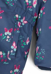 Jachetă de marină cu un model floral, având fluturi roz și turcoaz, talie elastică și o textură de țesătură moale și netedă.