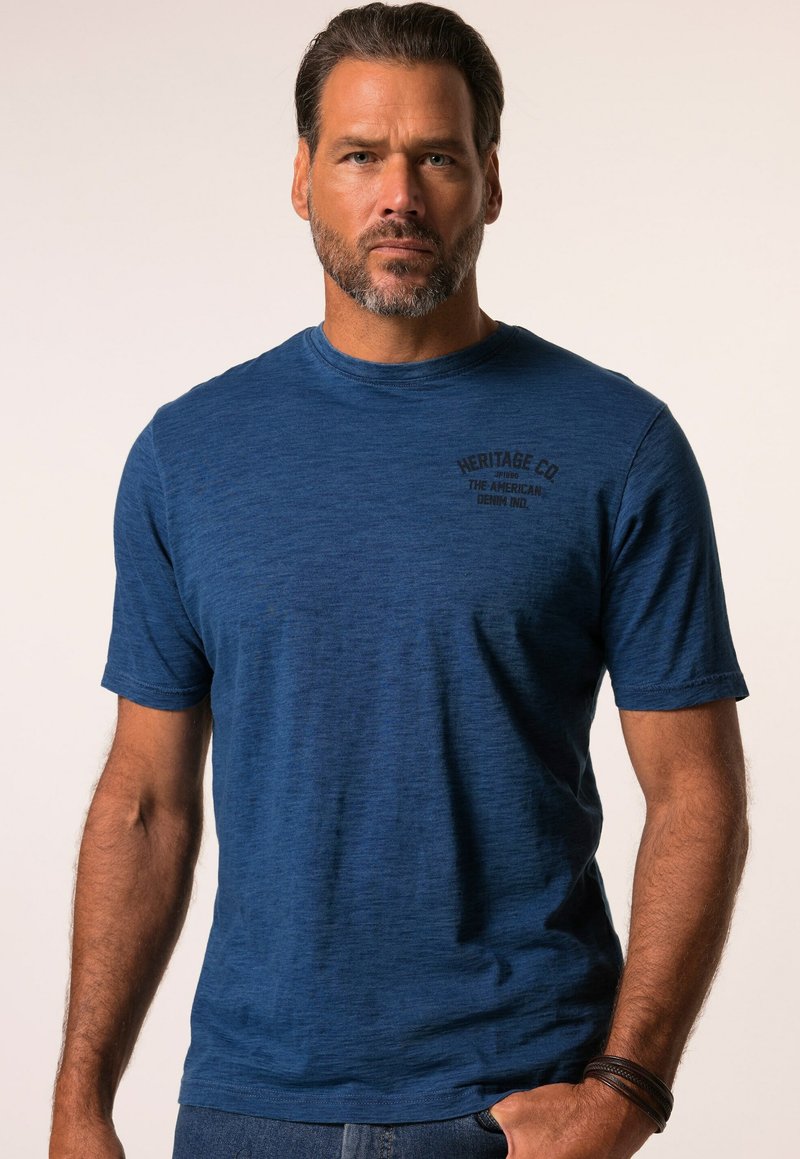 Modrá krátkosrstá trička z texturované látky, s kulatým výstřihem a černým potiskem loga v levém horním rohu.