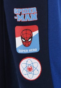 Marineblauwe stof met drie grafische patches: de tekst "SPIDER-MAN", een rood en blauw Spider-Man logo, en een atoomontwerp met een spin.
