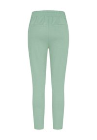 Pantalons de survêtement vert menthe avec une taille élastique, coupe slim et deux poches arrière. Tissu doux avec une texture lisse et sans motifs visibles.