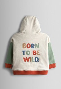 Capuchontrui in crème met groene en roestbruine mouwen. Voorzien van geborduurde tekst "BORN TO BE WILD" in meerkleurige letters. Gemaakt van katoen.