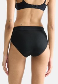 Hochgeschnittene schwarze Unterwäsche aus glattem Material mit nahtlosem Design und elastischem Bund, ausgestattet mit feinen Nahtdetails an den Kanten.