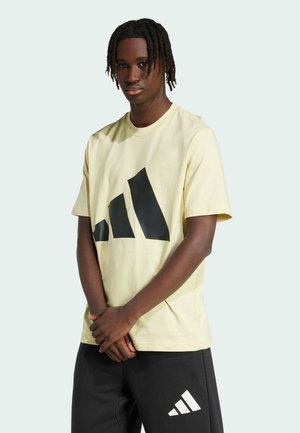 Camiseta de algodón amarilla con un gran logo negro en un diseño triangular. Combinada con pantalones negros que tienen un logo blanco. Estilo de cuello redondo simple.