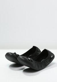 Svarta ballerina-skor i slätt läder, med en samlad elastisk öppning, en liten rosett som detalj och en strukturerad gummisula.