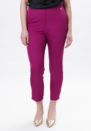 Aansluitende cropped broek in levendig magenta stof, met een gladde textuur, een ritssluiting aan de voorkant en subtiele gouden accenten bij de tailleband.
