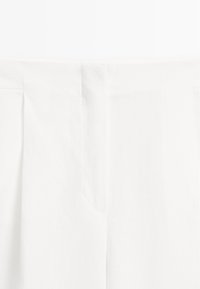 Witte linnen stof met een gladde textuur, met een rechte snit en subtiele plooien bij de tailleband. Het ontwerp is minimalistisch en eenvoudig.