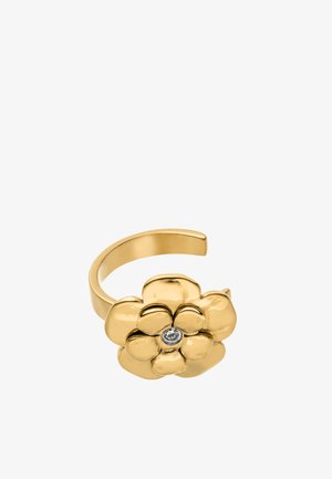 Verstellbarer goldfarbener Ring mit einem polierten Blumendesign und einem klaren Edelstein in der Mitte vor weißem Hintergrund.
