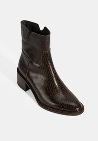 Braune Leder-Ankelstiefel mit Krokodilmuster, spitzer Zehe und niedrigem Blockabsatz. Elegantes Design mit Ausschnitten an den Seiten.