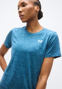 Μπλε αθλητική κοντομάνικη μπλούζα από υφασμάτινη υφή, με λευκό λογότυπο Under Armour στο αριστερό στήθος.